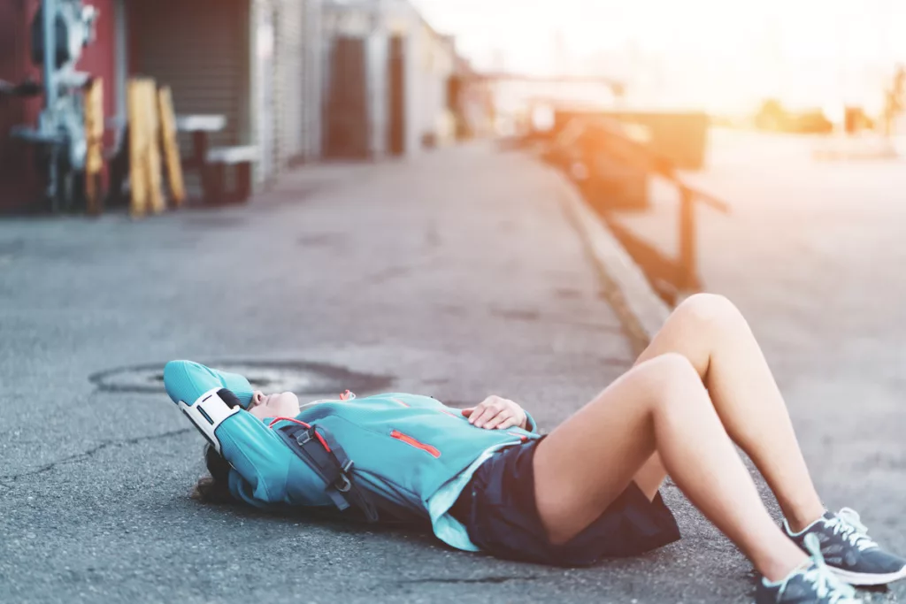 Tired woman lying and resting after workout in city industrial area